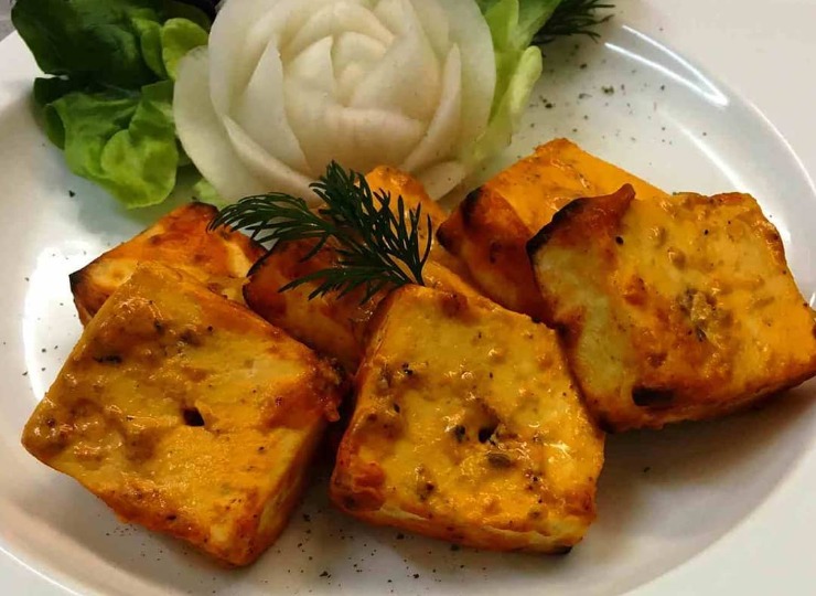 A plate with Tandoori paneer garnished with a flower made from vegetable